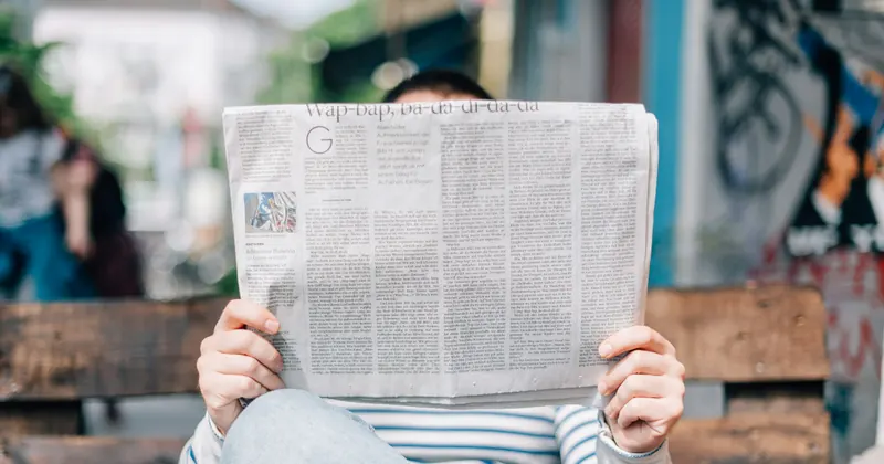 Persona leyendo un periódico y tomando notas para contrastar una información