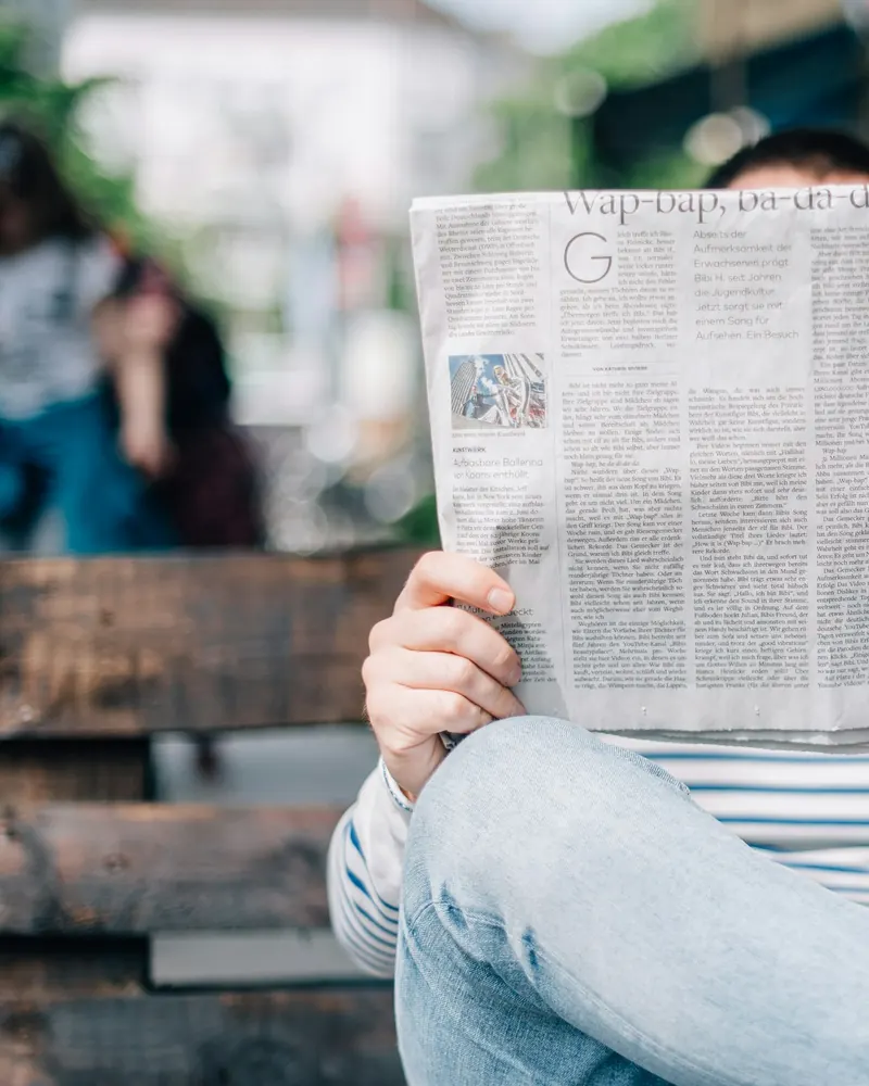 Persona leyendo un periódico y tomando notas para contrastar una información